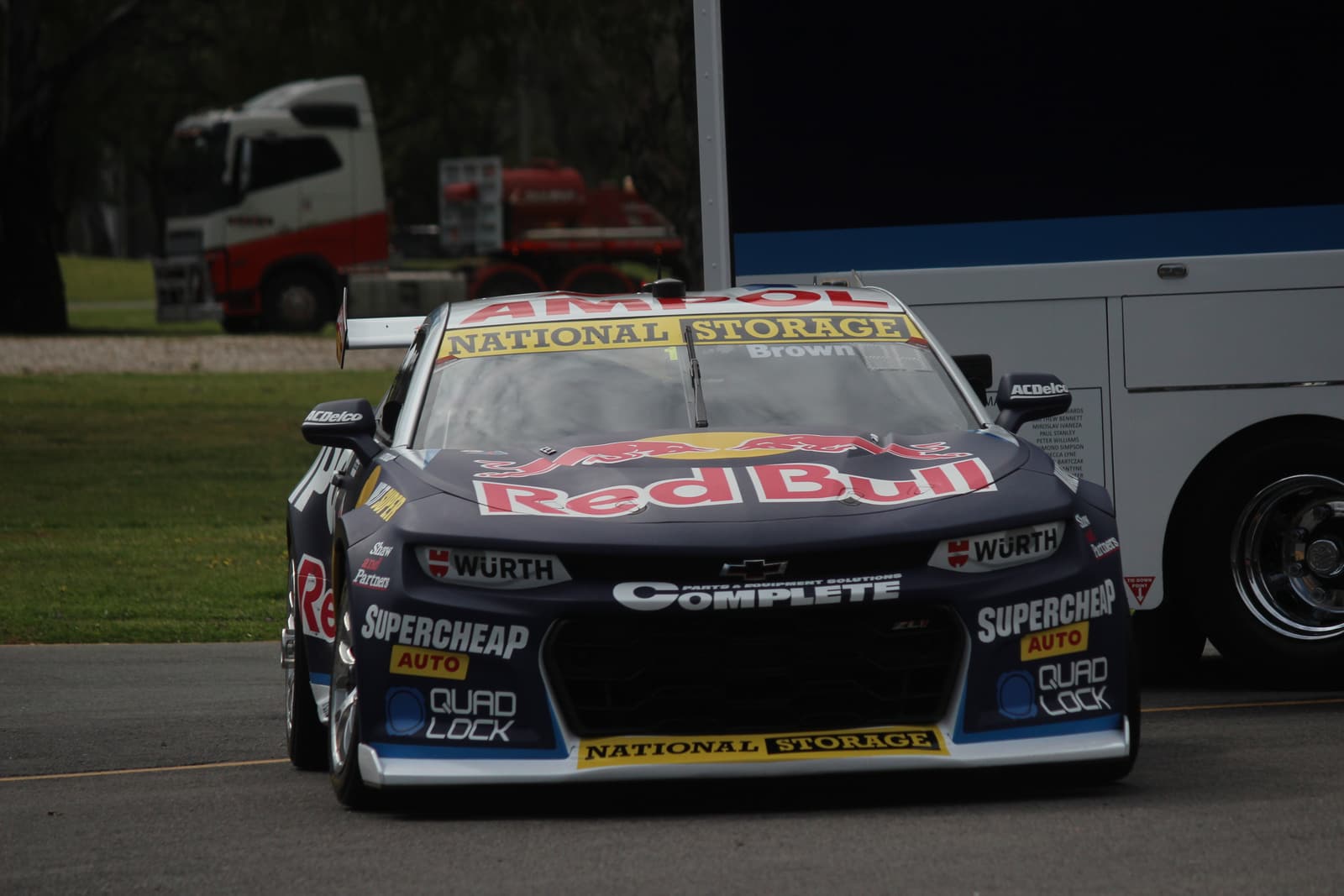 Supercar parked beside its race transporter in the paddock